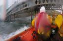 The lifeboat team saving the man clinging to the pier.