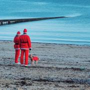 Santa's and their dog pause on Llandudno beach